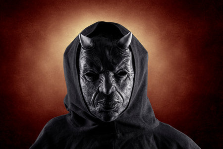 Portrait of a bad devil with horns on head over dark fiery backgroundの写真素材