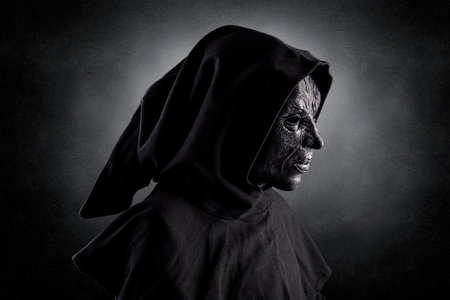 Scary figure with hooded cloak over dark misty background with clipping pathの写真素材