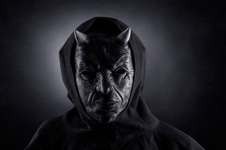 Portrait of a bad devil with horns on head over dark misty background