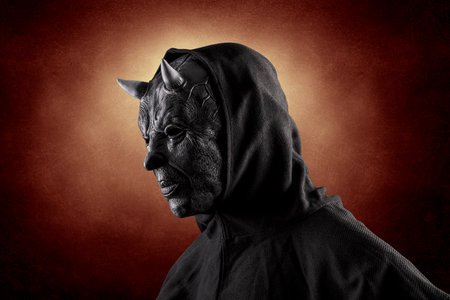 Portrait of a bad devil with horns on head over dark fiery backgroundの写真素材
