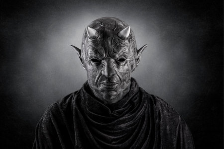 Portrait of a bad devil with horns on head over dark misty backgroundの写真素材