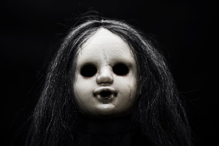 Scary doll face on dark backgroundの写真素材