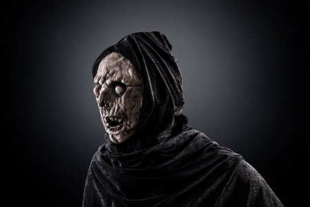 Scary zombie in black cloth on dark background. Halloween concept.