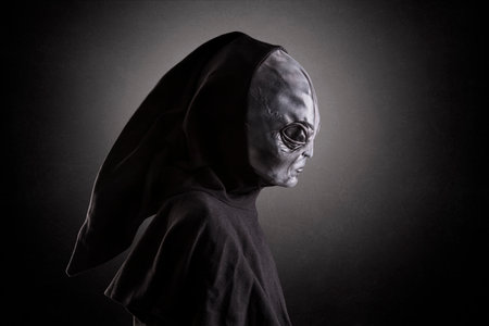 Mysterious humanoid alien at night over dark misty background