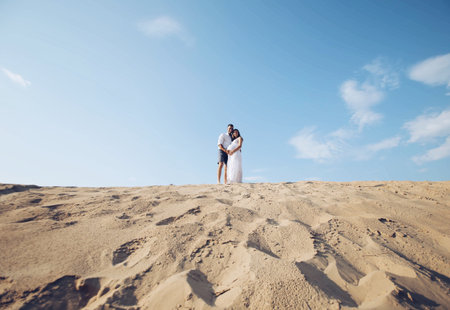Portrait of caucasian family with baby in white clothes are standing on sands dune. Pregnant mpther. Newbornの写真素材