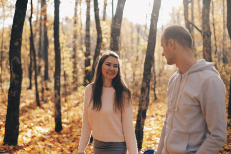 A happy couple looking at eachother and walking in the forest holding hands.の写真素材