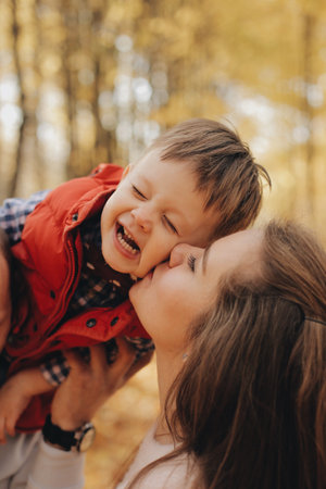 Little child sitting on fathers shoulders. Mother kisses her sonの写真素材