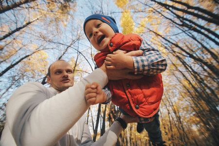 Father playing with his son. Dad keeps his son in arms.の写真素材