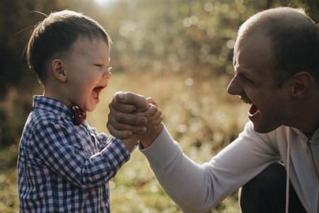 Handsome young father son competing in arm wrestling with cheerfull young son with bow tie.の写真素材