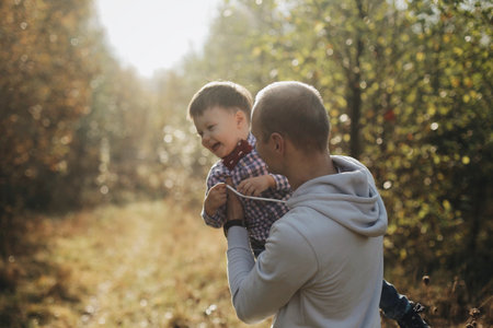 Young father holding his little son circling on hands. Autumn nature.の写真素材