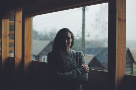 Young beautiful girl in the village. Model on background of a wooden house in the village. Dark light.の写真素材