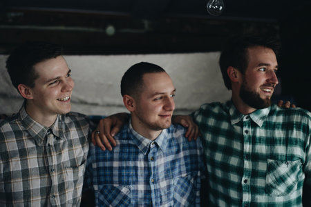 Belarus, Gomel - December 20, 2017: Three young smiling man, model of fashion, wearing a plaid. Boys standing toghether and look away.のeditorial素材