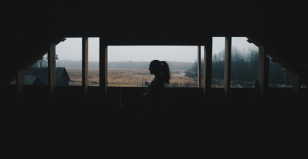 Silhouette of young beautiful girl in the village. Model on background of a forest. Woman girl in front of the window.の写真素材