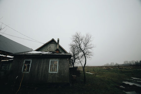 Wooden old house in spring. Dirty nature around. House in the villageの写真素材