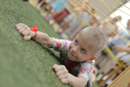 Belarus, Bobruisk - june 20, 2018: Close up boy lies on grass. Little boy play on the playground. Artificial turfのeditorial素材