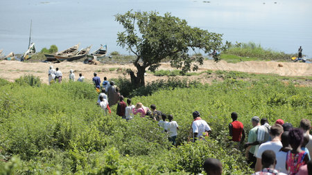 KENYA, KISUMU - MAY 20, 2017: Big group of African and Caucasian people are going together to the shore of the sea.のeditorial素材