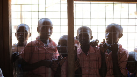 KENYA, KISUMU - MAY 20, 2017: Beautiful African boys peer into a house through the lattice on window.のeditorial素材