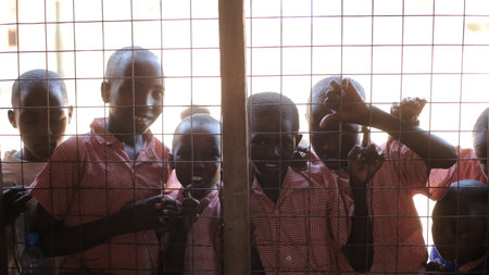KENYA, KISUMU - MAY 20, 2017: Beautiful African boys peer into a house through the lattice on window.のeditorial素材
