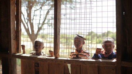 KENYA, KISUMU - MAY 20, 2017: Beautiful African boys peer into a house through the lattice on window.のeditorial素材