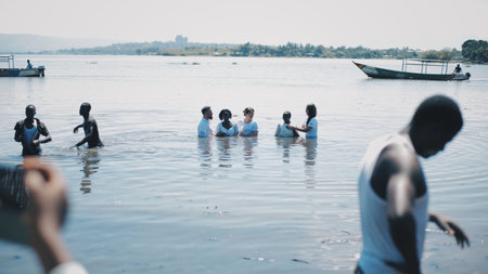 KENYA, KISUMU - MAY 20, 2017: Caucasian people baptize African people in white clothes in the water on shore of lake.のeditorial素材