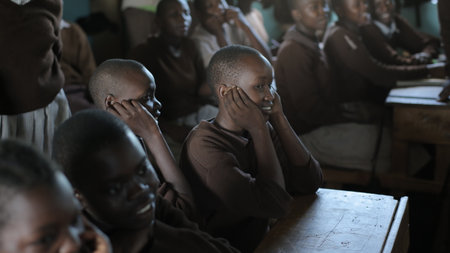 KENYA, KISUMU - MAY 20, 2017: Group of african children in uniform sitting in classroom and looking straight, smiling.のeditorial素材