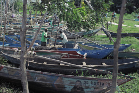KENYA, KISUMU - MAY 20, 2017: Two african man preparing his boat before work. People taking shower in the lake.のeditorial素材