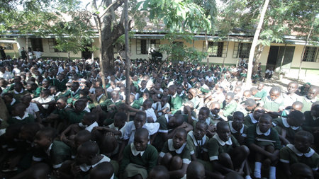 KENYA, KISUMU - MAY 23, 2017: Big crowd of African children in uniform sitting on a ground outside near school.のeditorial素材