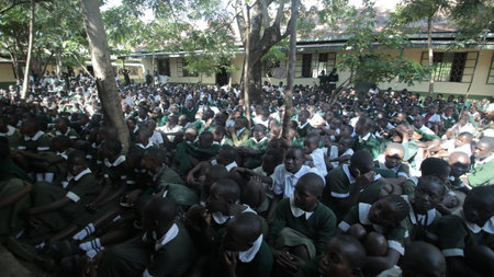 KENYA, KISUMU - MAY 23, 2017: Big crowd of African children in uniform sitting on a ground outside near school.のeditorial素材