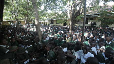 KENYA, KISUMU - MAY 23, 2017: Big crowd of African children in uniform sitting on a ground outside near school.のeditorial素材