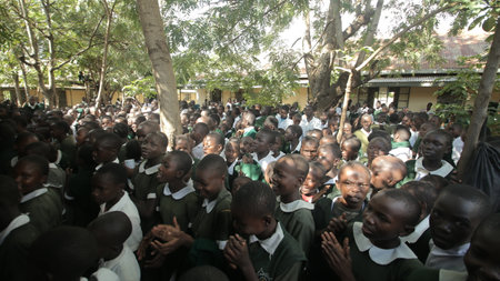 KENYA, KISUMU - MAY 23, 2017: Big crowd of African children in uniform sitting on a ground outside near school.のeditorial素材