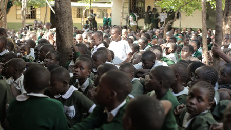 KENYA, KISUMU - MAY 23, 2017: Big crowd of African children in uniform sitting on a ground outside near school.のeditorial素材