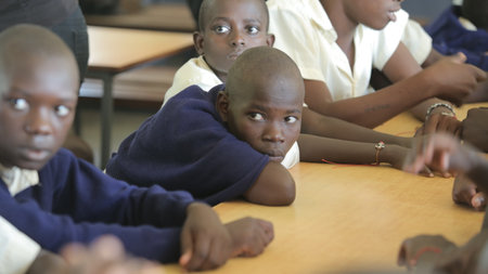 KENYA, KISUMU - MAY 23, 2017: Close-up view of three african boys in uniform sitting in classroom in schoolのeditorial素材