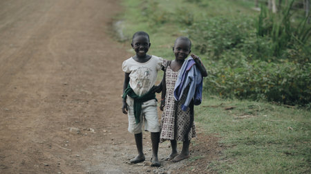 KENYA, KISUMU - MAY 20, 2017: View through leafs of african girls playing with tires on the road. Kids having fun together.のeditorial素材