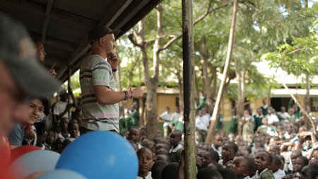 KENYA, KISUMU - MAY 23, 2017: Caucasian men standing and talking in African school to group of children.のeditorial素材
