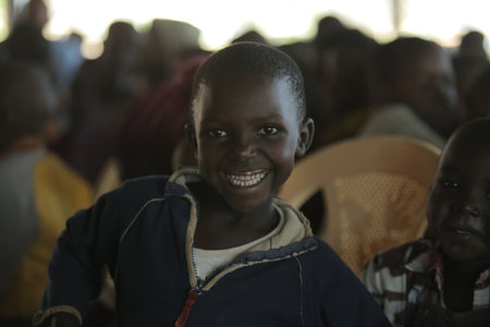 KENYA, KISUMU - MAY 23, 2017: Portrait of happy african girl sitting inside with group of children and dancing, smiling.のeditorial素材
