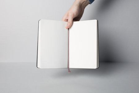 Hands holding opened Notebook. Blank paper Mock-up.の写真素材