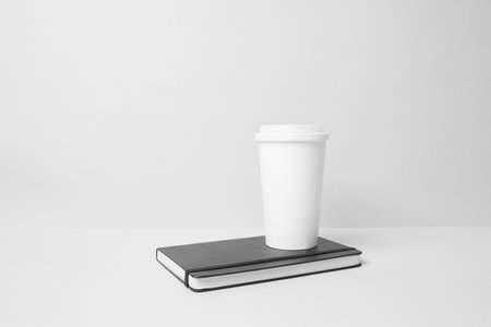 Blank paper cup on the top of the moleskineの写真素材