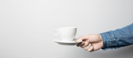 Hand in blue shirt is holding white coffee cupの写真素材