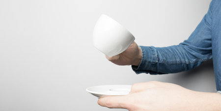 Hand in blue shirt is holding white coffee cupの写真素材