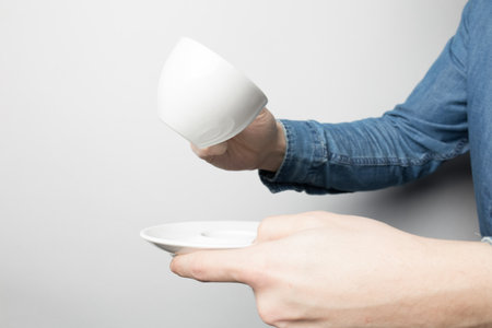 Hand in blue shirt is holding white coffee cupの写真素材