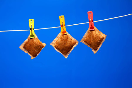 Three teabags on a washingline, with a blue backgroundの写真素材