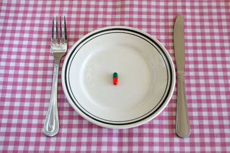 Capsules on a plate with a knife and fork, signifying diating.の写真素材