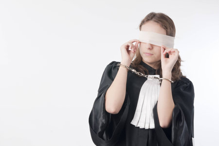 Young law school student holding statute books blindfolded and handcuffedの写真素材