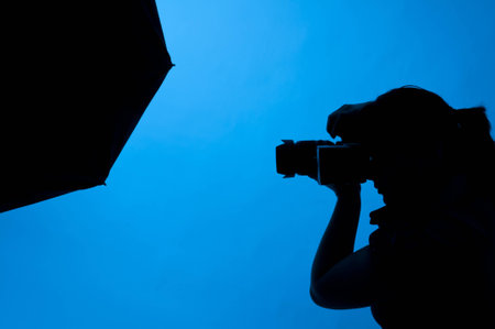 Photographer shooting in studio on a blue backgroundの写真素材