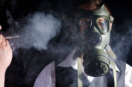 Man wearing a gas mask for protection against cigarette smokeの写真素材