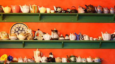Collection of teapots on green shelf against orange wallの写真素材