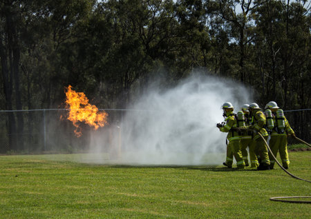Team of fire fighters dousing flames with water hoses