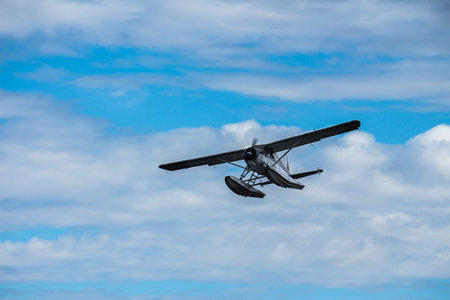 Seaplane in flight against blue cloudy skyの写真素材