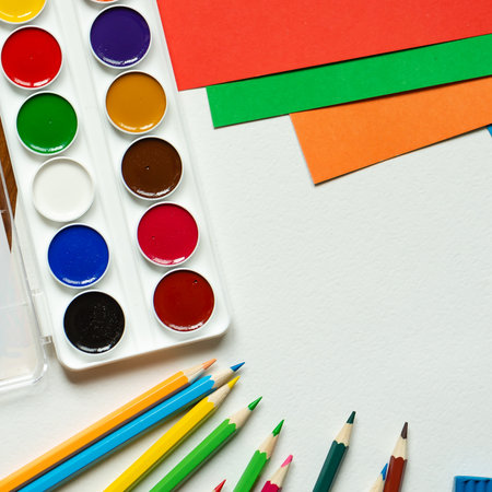 Working area for a child with an album of paints, crayons, plasticine, scissors, brushes, pencils, glue and colored paper.の写真素材