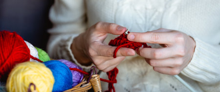 A girl in a white sweater knits with knitting needles. Womens hands knit with knitting needles....